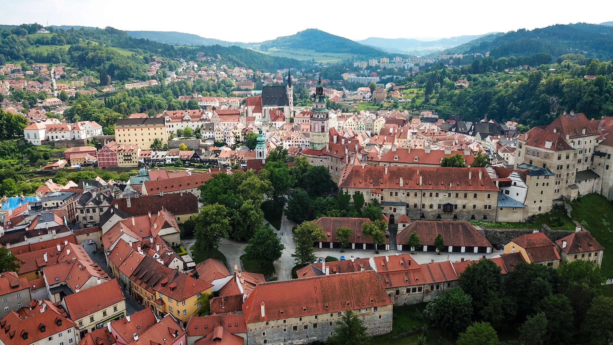 Aerial view of Český Krumlov with red roofs, castle buildings and green hills
