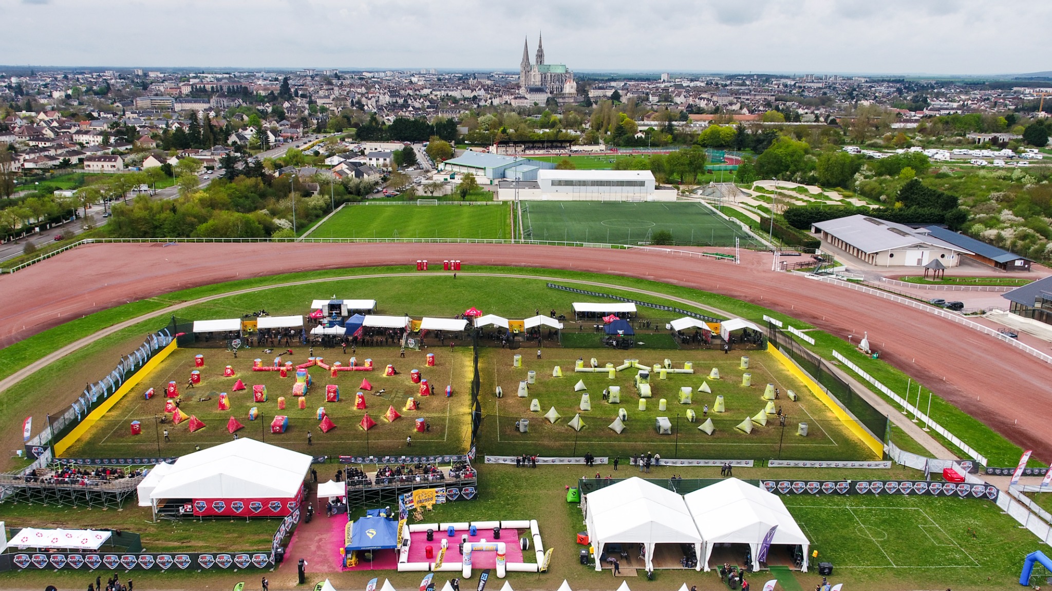 Aerial view of a sporting event inside a track complex with Chartres visible beyond