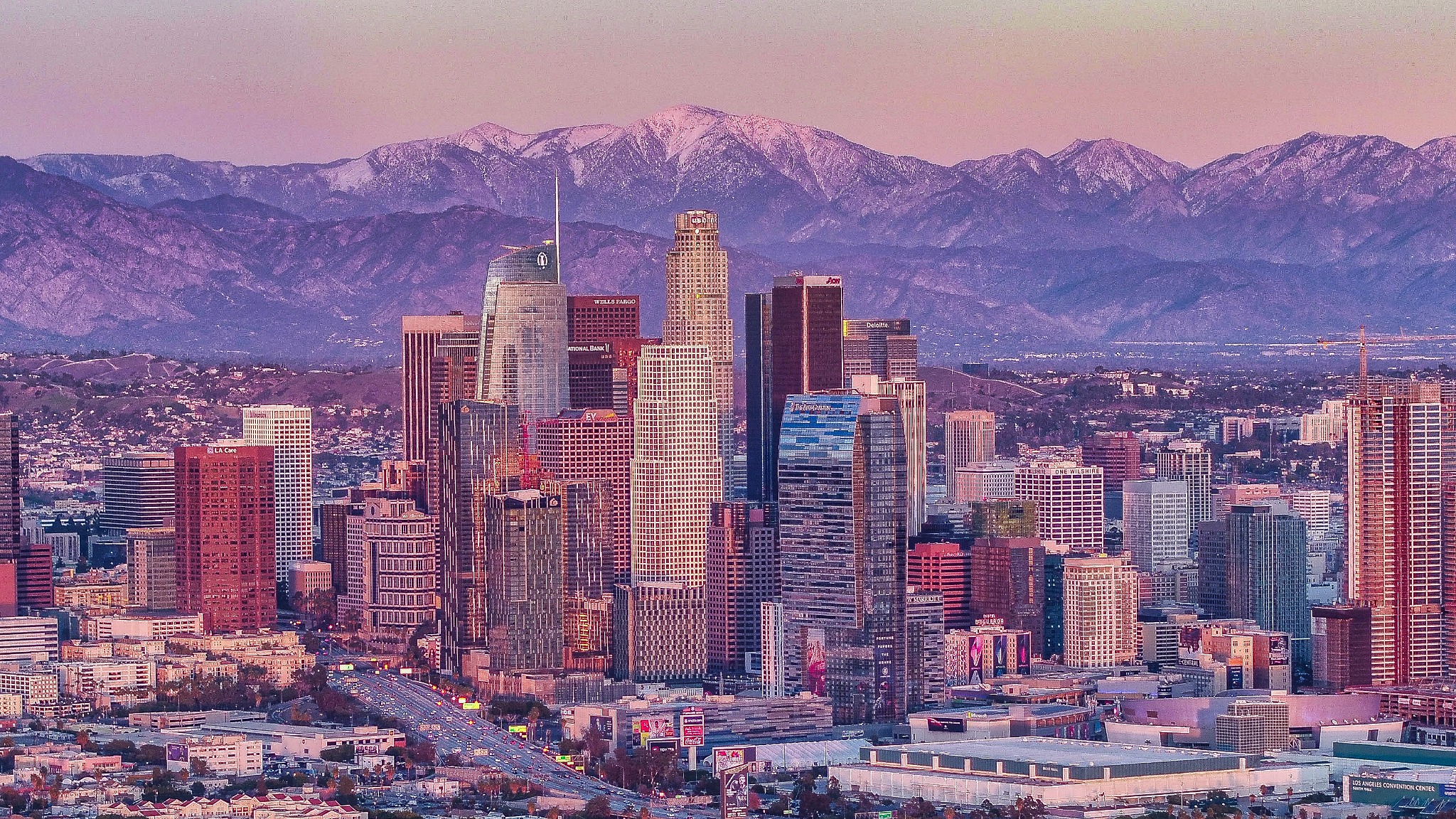 Purple twilight view of downtown Los Angeles with snowy mountains