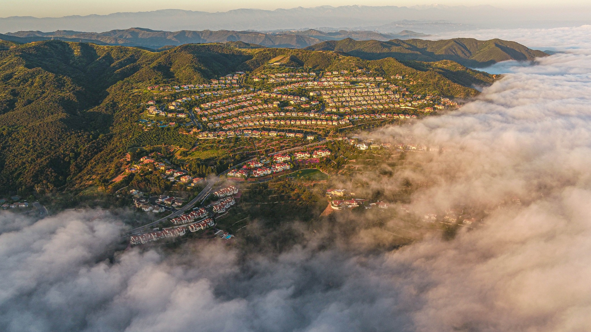 Pacific Palisades hillside community surrounded by mountain ridges and low clouds